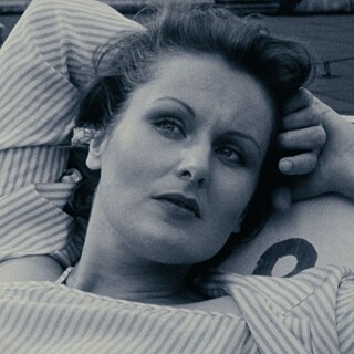 Black-and-white close-up of a white woman, looking affectionate with her arms clasped behind her head