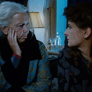 An older white woman and a younger white woman look at each other.