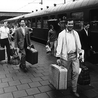 En blanco y negro, gente con maletas en un andén de tren