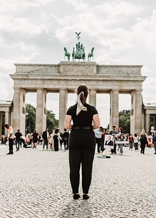 a woman stand in front of the brandenburg gate with her back to the camera