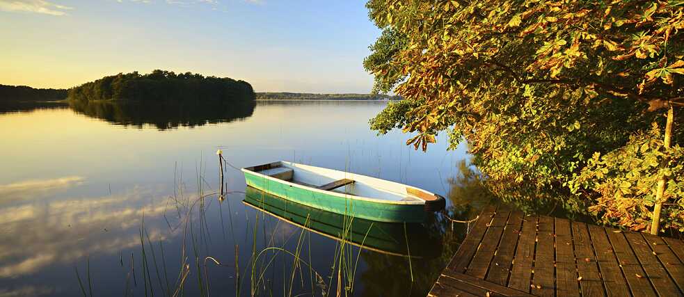 A tranquil lake with a jetty and a rowing boat on an autumn evening, Großer Lychensee, Uckermark