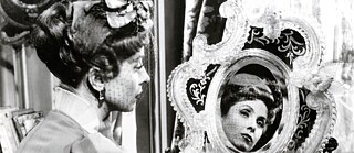 Eine Frau betrachtet sich im Spiegel.