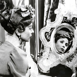 Eine Frau betrachtet sich im Spiegel.