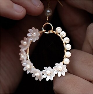 runder Ohrring mit Blumen und Finger