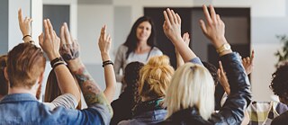 Hochgereckte Arme im Klassenraum