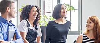 Eine Gruppe junger Erwachsene lächeln sich gegenseitig
