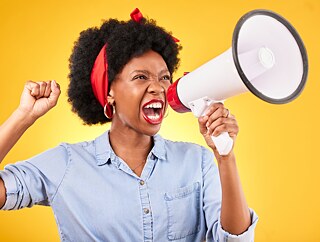 Frau, Megafon und Protest; Stimme, Nachrichten, Rundfunk oder Durchsage; Faust und gelber Hintergrund. Wütender Afrikaner, Student oder Redner in einer Position der Macht, Führung und Aufmerksamkeit oder Gerechtigkeit in einem Studio