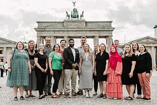 a woman stand in front of the brandenburg gate with her back to the camera