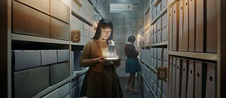 Filmszene aus „The Ordinaries“: Eine junge Frau hält leuchtendes Gerät im Archiv, kleine Figuren erscheinen daraus, Reihen voller Aktenordner