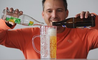Ein Mann füllt Bier und Limonade in einen Maßkrug mit Trennwand.
