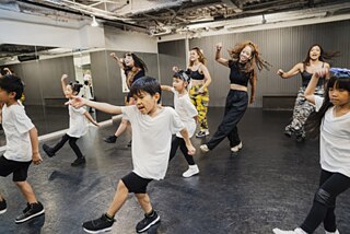 Kinder und Jugendliche in einem Tanzstudio beim Hip-Hop-Tanzen. Sie sind fröhlich und ausgelassen.