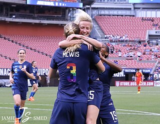 Une photo de Megan Rapinoe et Sam Mewis se tombant dans les bras dans un stade. 