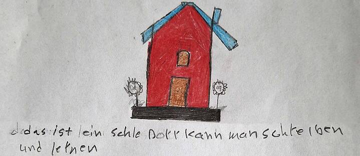 Eine Buntstiftzeichnung von einem roten Haus mit einem blauen Dach mit einer von Hand geschriebenen Bildunterschrift.