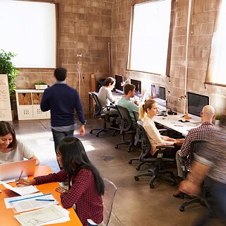 Mehrere Personen arbeiten an Computern in einem offenen Büro.