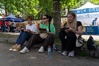 Ira (na pravej strane) s priateľkami počas obeda od dobrovoľníkov oproti svojmu zničenému domu