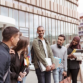 Eine Gruppe von Schüler*innen kommt aus einem Schulgebäude heraus und wirkt entspannt, nachdem sie die Deutschprüfung des Goethe-Instituts an ihrer Schule abgelegt haben.