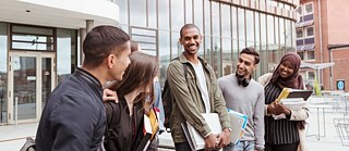 Eine Gruppe von Schüler*innen kommt aus einem Schulgebäude heraus und wirkt entspannt, nachdem sie die Deutschprüfung des Goethe-Instituts an ihrer Schule abgelegt haben.