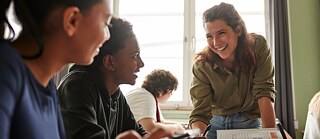 Eine Deutschlehrerin erklärt ihren Schüler*innen freundlich die deutsche Grammatik.​