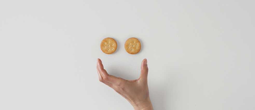 A smiling smiley face with two cookies for eyes and an open hand for a mouth