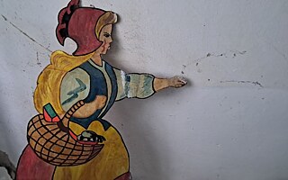 Ručně vyrobená figurka ukrajinské ženy, která „kráčí“ kolem prasklin ve staré omítce
