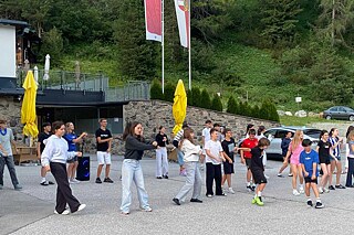 Jugendliche tanzen ausgelassen auf einem gepflasterten Hof.