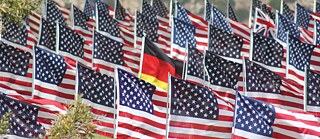Foto einer deutschen Flagge, umgeben von US-Flaggen auf einer Wiese