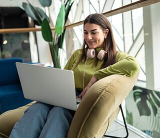 junge Frau arbeitet lächelnd an Laptop