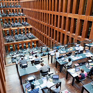 Many people study at desks in a multi-storey library.