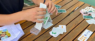 Auf einem Gartentisch wird mit Karten gespielt.