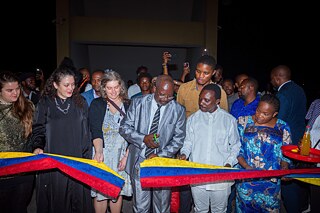 Banddurchtrennung bei der Vernissage der Ausstellung „Elima-NoBody“ im Musée d'Art Contemporain et Multimédia in Kinshasa, umgeben von Gästen und Kunstinteressierten.