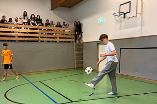 Ein Junge führt Kunststücke mit einem Fußball vor.