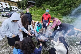 Jugendliche grillen Marshmallows über einem offenen Holzfeuer.