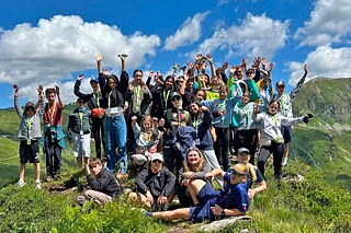 Eine Gruppe Jugendlicher bei einer Wanderung grüßen in die Kamera.