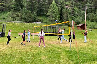 Jugendliche spielen Volleyball auf einer Wiese.