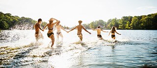 Junge Leute rennen zum Baden ins Wasser