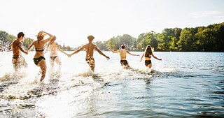 Junge Leute rennen zum Baden ins Wasser
