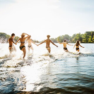 Junge Leute rennen zum Baden ins Wasser