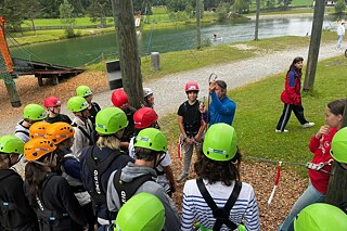 Ein junger Mann erklärt die Sicherheitsvorkehrungen und die Ausrüstung im Kletterpark.