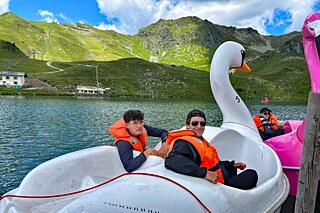 Jugendliche in Tretbooten, die die Form von einem Schwan und einem Flamingo haben.