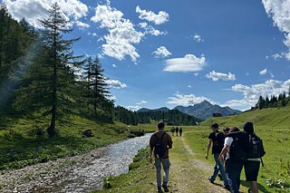 Jugendliche wandern an einem Bach entlang.