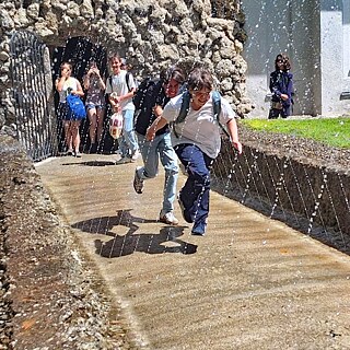 Kinder laufen durch die Fontänen in den Wasserspielen Hellbrunn.