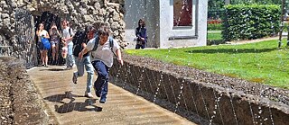 Kinder laufen durch die Fontänen in den Wasserspielen Hellbrunn.