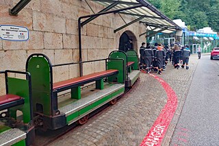 Eine Bergbahn vor einem Gegäude und Jugendliche