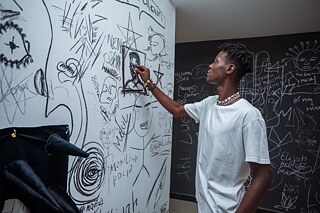 Besucher ergänzt Zeichnungen partizipative Kunstwand mit Zeichnungen und Besucherbeiträgen in der Ausstellung „Elima-NoBody“ im Musée d'Art Contemporain et Multimédia in Kinshasa.