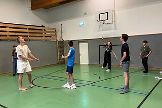 Jugendliche spielen Ball in einer Halle.