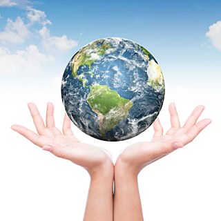 Über zwei Händen schwebt der Planet Erde.