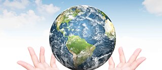 Über zwei Händen schwebt der Planet Erde.