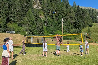 Jugendliche spielen Volleyball auf einer Wiese.
