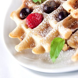 Waffeln mit Himbeeren, Blaubeeren, Puderzucker und Minzblättchen
