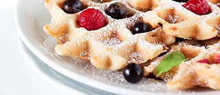 Waffeln mit Himbeeren, Blaubeeren, Puderzucker und Minzblättchen
